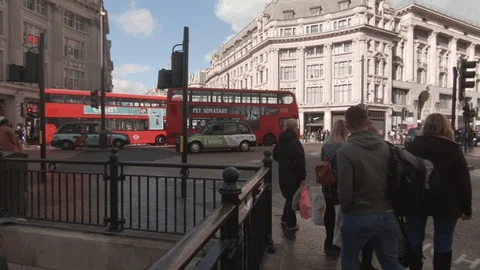 Camera pans from the Oxford Circus junction to a newspaper seller 스톡 동영상 128866137