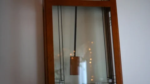 Camera pans up past a swinging pendulum to a ticking clock Stock Footage 94773649
