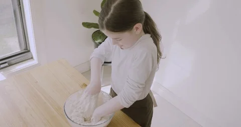 Camera pans from slightly overhead as child kneads and mixes bread dough by hand Stock-Footage 115480458