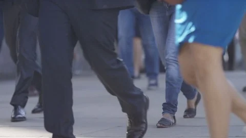 Camera pans slowly as pedestrian commuters walk to work, in slow motion 库存影片 77609366