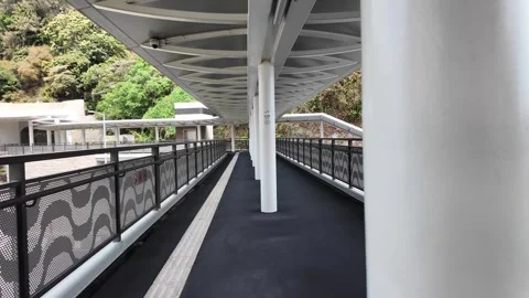 A camera pans through a modern covered walkway overlooking a green hillside. Stock Footage 333661565