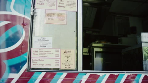 Camera pans up towards a food menu hanging off the side of a food truck Stock Footage 280142619