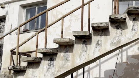 Camera pans up weathered concrete staircase beside deteriorating white building Stock Footage 346895290