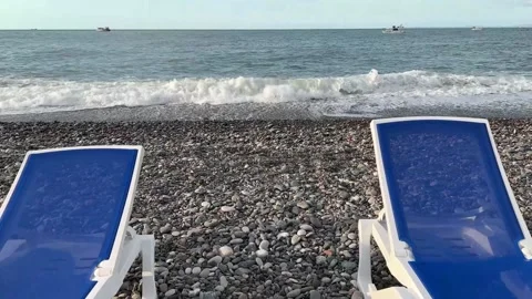 Camera passes between two sun loungers towards shore Stock Footage 250636757