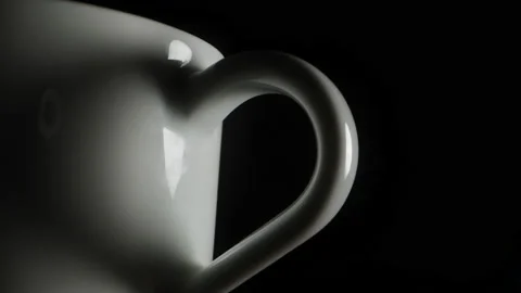 The camera passes through the handle of a white mug, in the dark, a heart-shaped Vidéo 220650146