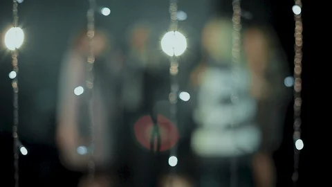 The camera peeps through the glowing lights as young people rejoice and dance Stock Footage 114627908