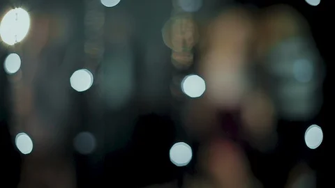 The camera peeps through the glowing lights as young people  rejoice and dance Stock Footage 114627965