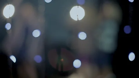 The camera peeps through the glowing lights as young people  rejoice and dance Vídeos de archivo 114627970