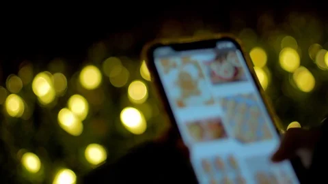 Camera Pull, Christmas Lights, Reveal, Girl Scrolling on Smartphone, 4K Stock Footage 120916433