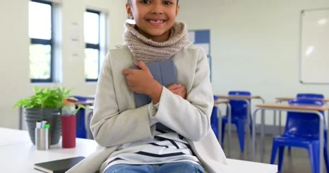 Camera pulling back African American child sitting on table in class holding Stock Footage 340751430