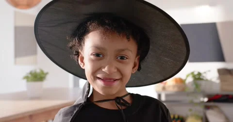 Camera pulling back African American child in kitchen in witch hat showing Stock Footage 345090069