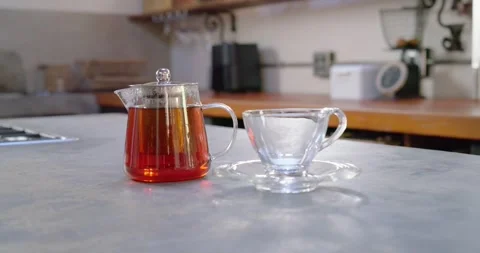 Camera is pulling back and tilting up, revealing glass teapot and empty teacup Stock Footage 337098886