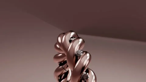 Camera pulling back, braided rose gold ring rotating up on studio table, showing Stock Footage 339194323