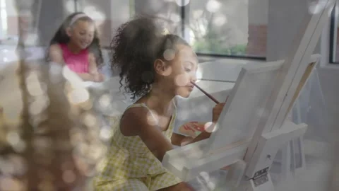 Camera pulling back, center girl in yellow dress dipping brush, painting canvas Stock Footage 332289142