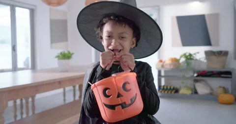 Camera pulling back, child tipping jack-o'-lantern bucket showing candy at home Stock Footage 344655656