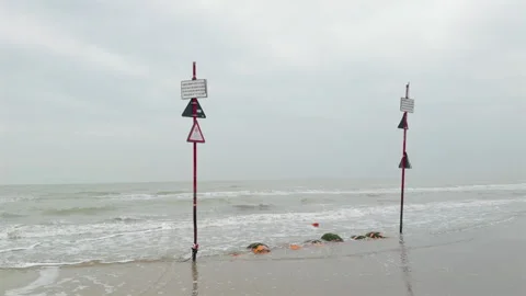 Camera pulling back from coastal warning signs on rough sea Stock Footage 340358121