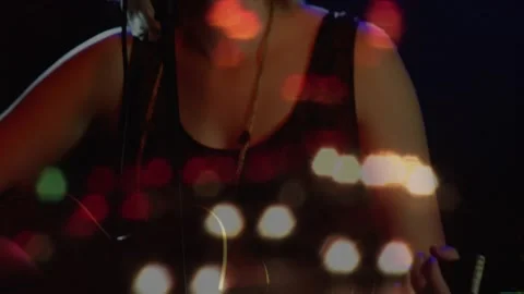 Camera pulling back female singer fretting strumming guitar leaning into mic Video stock 333902465