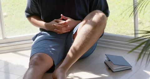 Camera pulling back, mid-adult African American man sitting by window, Stock Footage 344949715