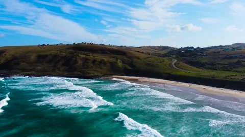 Camera pulling back over a beautiful, pristine beach and grass-covered hills of  Vídeos de archivo 315895579