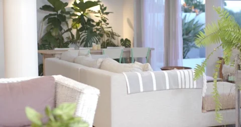 Camera is pulling back, panning right, revealing beige sofa and plants at home, Stock Footage 339495131