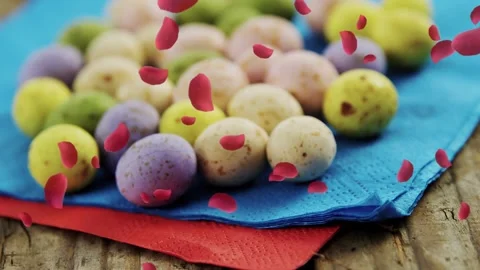 Camera pulling back, red petals drifting, revealing pastel eggs on layered Vídeos de archivo 330356122