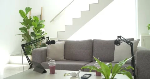 Camera is pulling back to reveal grey sofa and podcast setup as mic arms are Stock Footage 340974038