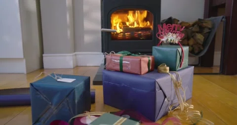 Camera is pulling back to reveal stacked wrapped presents by lit wood-burning Stock Footage 339268517