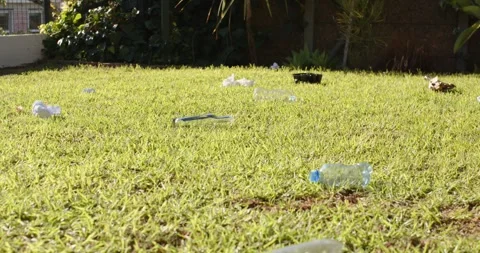 Camera pulling back is revealing crushed bottle and litter across sunny yard, Stock Footage 335895389