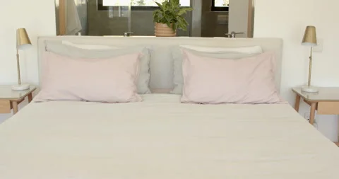 Camera is pulling back revealing made bed with pink pillows and ensuite bathroom Stock Footage 311020748
