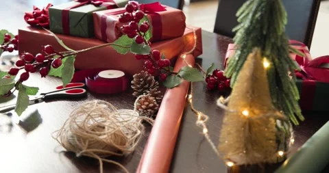 Camera pulling back, revealing twine, holly, red paper on dining table to show Stock Footage 344655801
