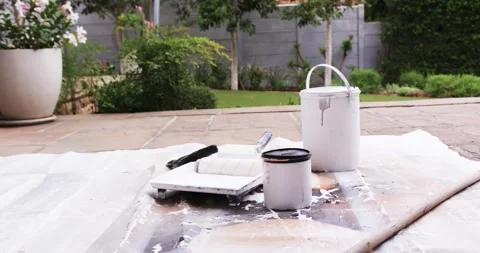 Camera pulling back revealing white bucket and roller, paint supplies on patio Stock Footage 340070290