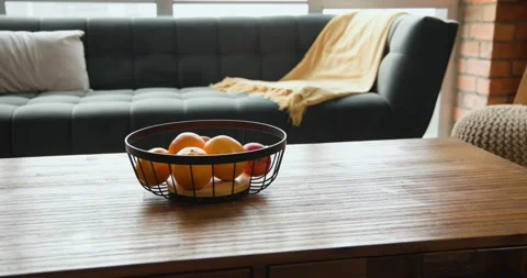 Camera is pulling back, revealing wire basket of oranges and apple on wood Stock Footage 340675326