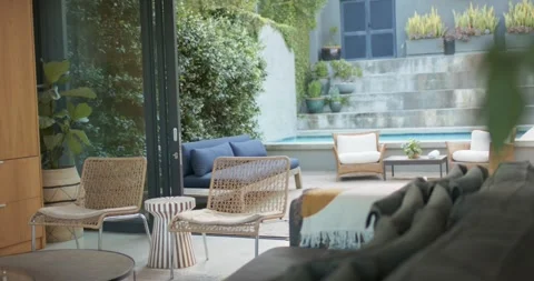 Camera is pulling back, revealing woven lounge chairs, blue sofa and plunge pool Stock Footage 340393593