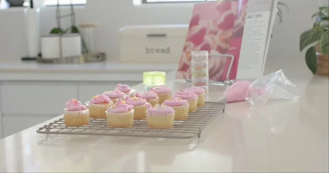 Camera is pulling back, showing cupcakes on cooling rack on glossy top, showing Stock Footage 335070716