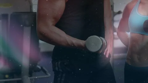 Camera pulling back while man and woman curling dumbbells together to Stock Footage 330621701