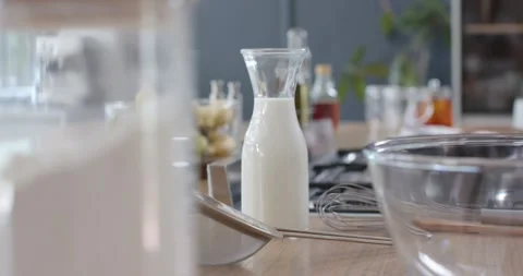 Camera pulling back while racking focus, milk carafe centering and whisk moving Stock Footage 336609544