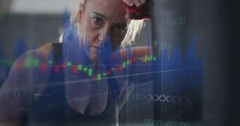 Camera pulling back, woman leaning on punching bag, chart tracking finance Stock Footage 330509188