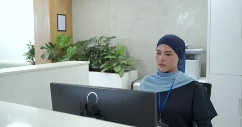 Camera pulling back, woman receptionist sitting at desk viewing screen, checking Stock Footage 336844631