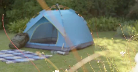 Camera pulling focus back revealing blue tent on lawn with blanket, pack, Stock Footage 340393820
