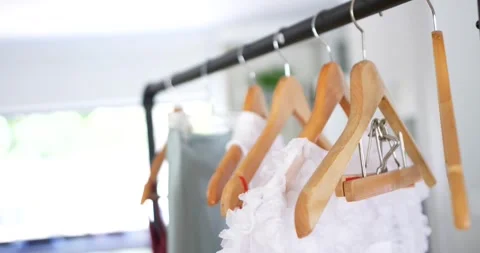 Camera pulling focus on black rail hangers revealing white ruffled garment near Stock Footage 344105655