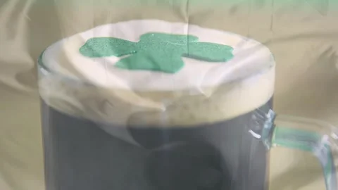 Camera pulling focus, clear glass mug revealing creamy foam and shamrock for Stock Footage 329908704