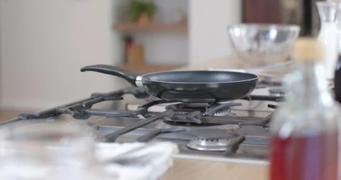 Camera is pulling focus, revealing nonstick frying pan on cooktop for product Stock Footage 342392726