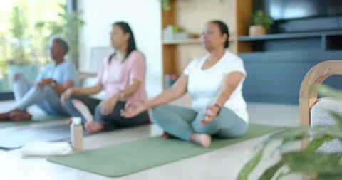 Camera pulling focus, senior and mature African American women meditating on Stock Footage 345213710