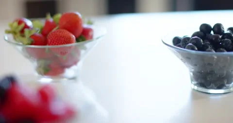 Camera pulling focus toward left glass bowl, revealing strawberries and Stock Footage 344326734