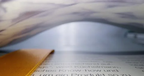 Camera pulling out of a closed print magazine. Macroshot - Red Cinema camera Stock Footage 130309187