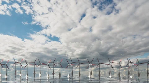 Camera pulls back through rotating blades of a wind turbine in an offshore wind Stock Footage 256980209