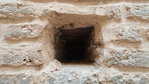 Camera pulls back through a small hole in an old wall - Mud Wall and Aged Brick Stock Footage 339811485