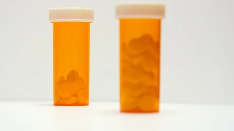 Camera pulls focus on pill bottles on white background. Stock Footage 108033034