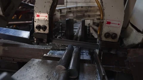 Camera pulls out from horizontal bandsaw cutting steel rods in shop Stock Footage 306954501