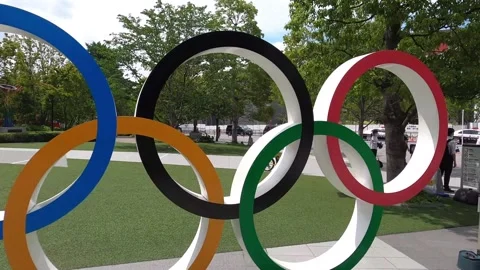 Camera pushes through the Olympic Rings Symbol in front of Olympic Stadium Stock Footage 156379637
